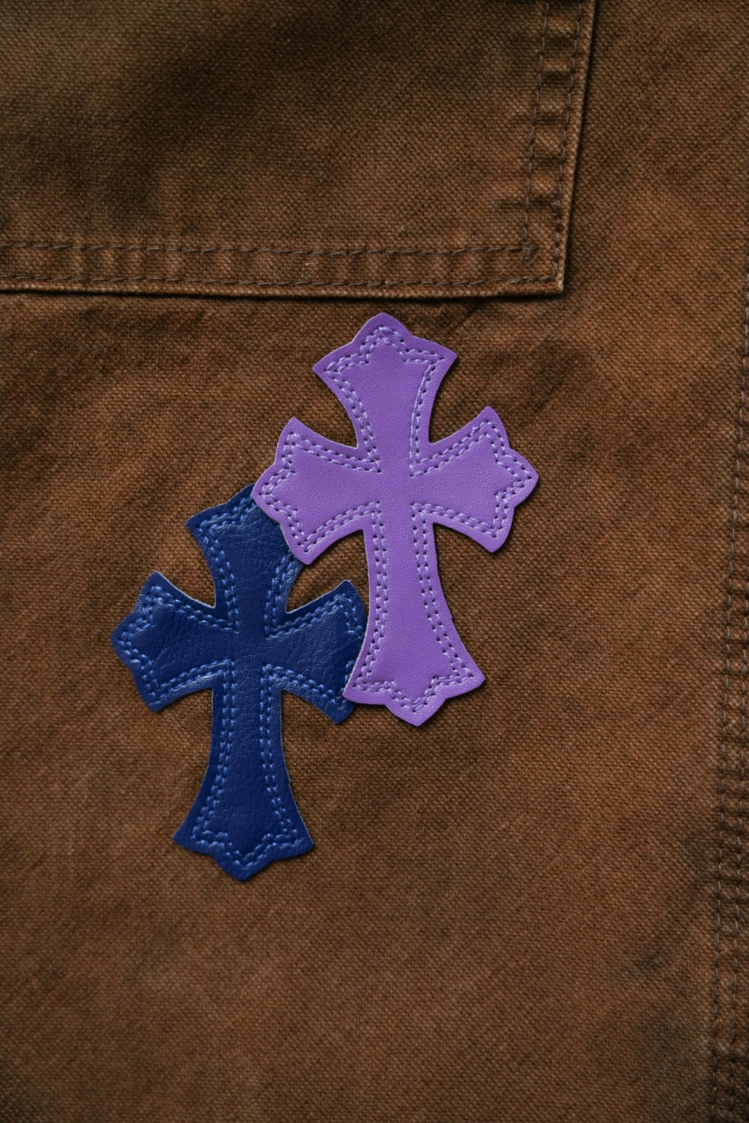 Close-up of brown jeans fabric with purple and blue cross patch