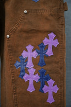 Brown jeans back close-up with purple cross patches and blue cross accents
