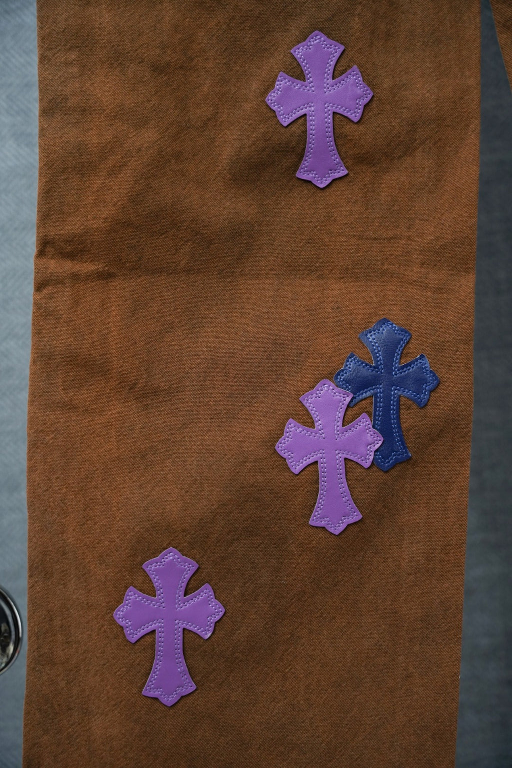 Brown Chrome pants close-up with purple and blue cross patches
