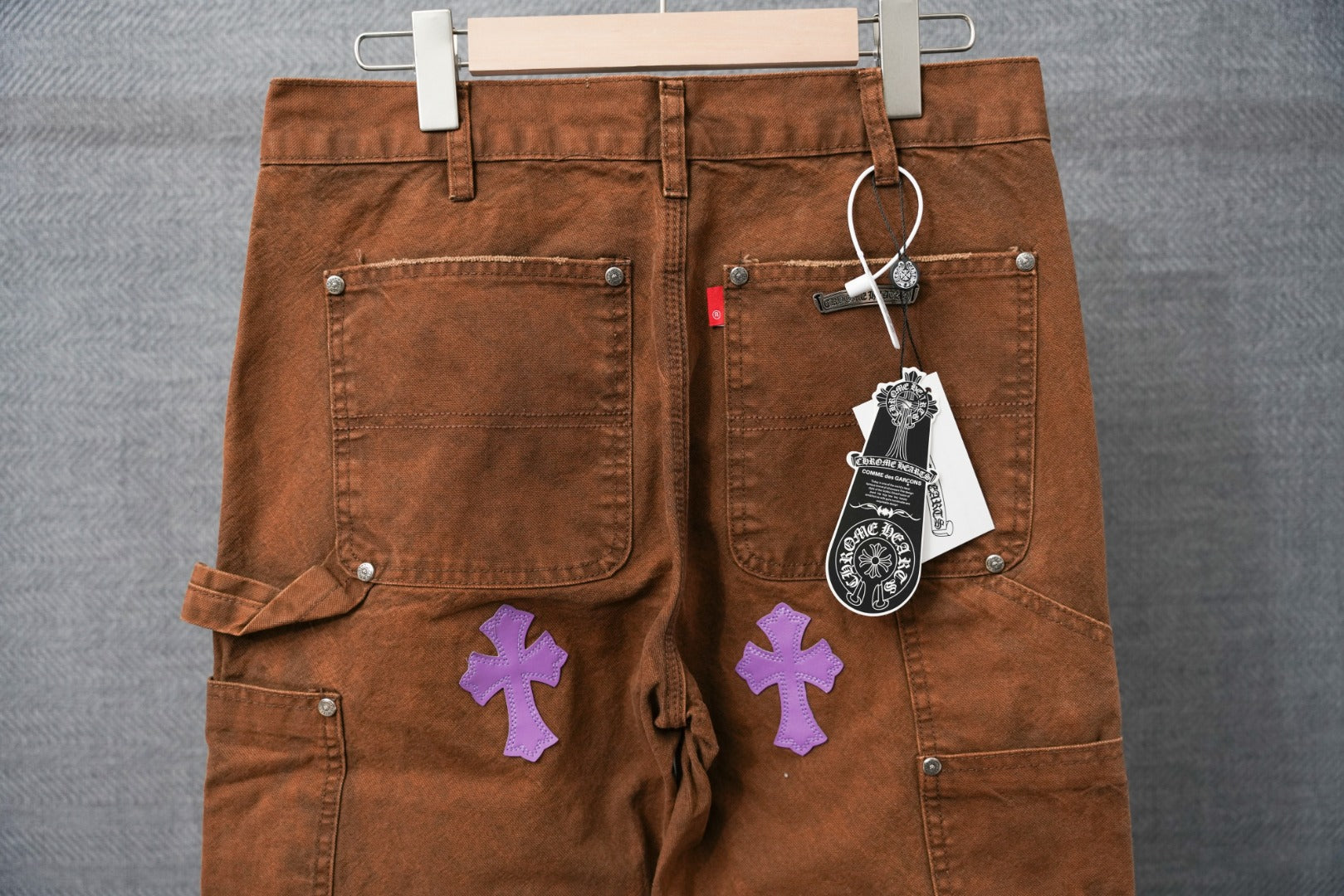 Brown Chrome pants with flap cargo pockets, buttons, and purple cross patches