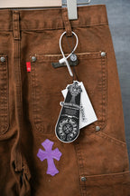 Brown Chrome pants with front pockets, metal buttons, and purple cross appliques