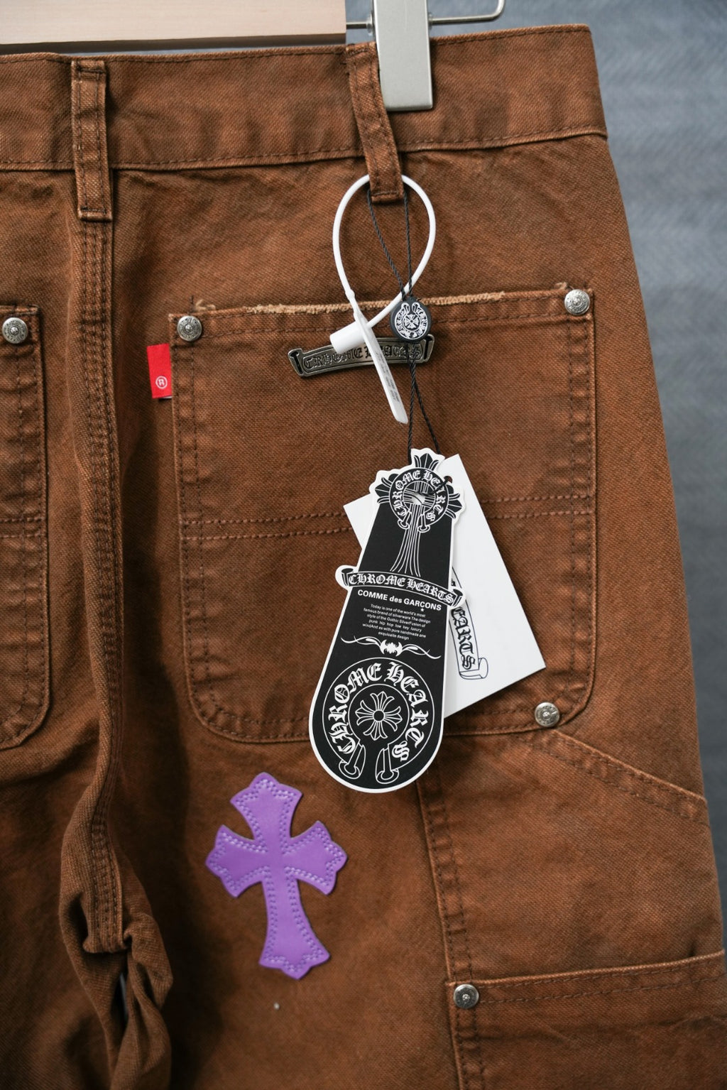 Brown pants with belt loops, cargo pockets, and cross patches; hanging tag visible