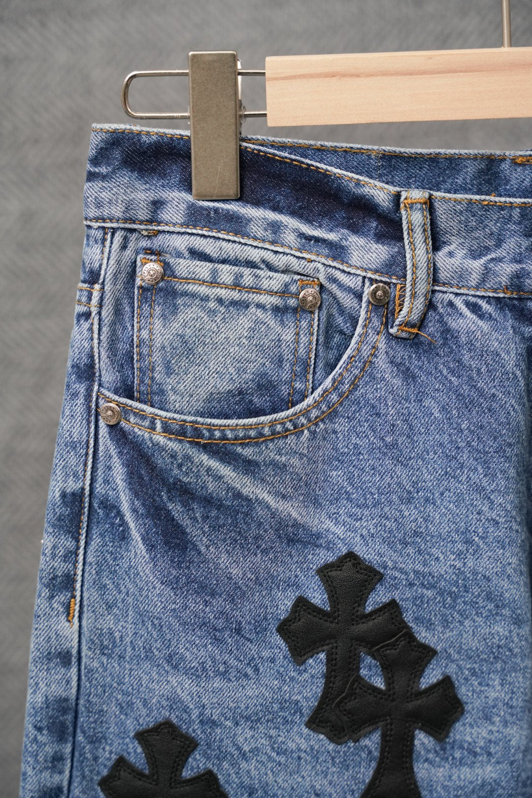 Light blue denim pants with front pockets and black cross patch applique