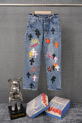 Blue denim pants with colorful graphic patches and belt loops, front view.