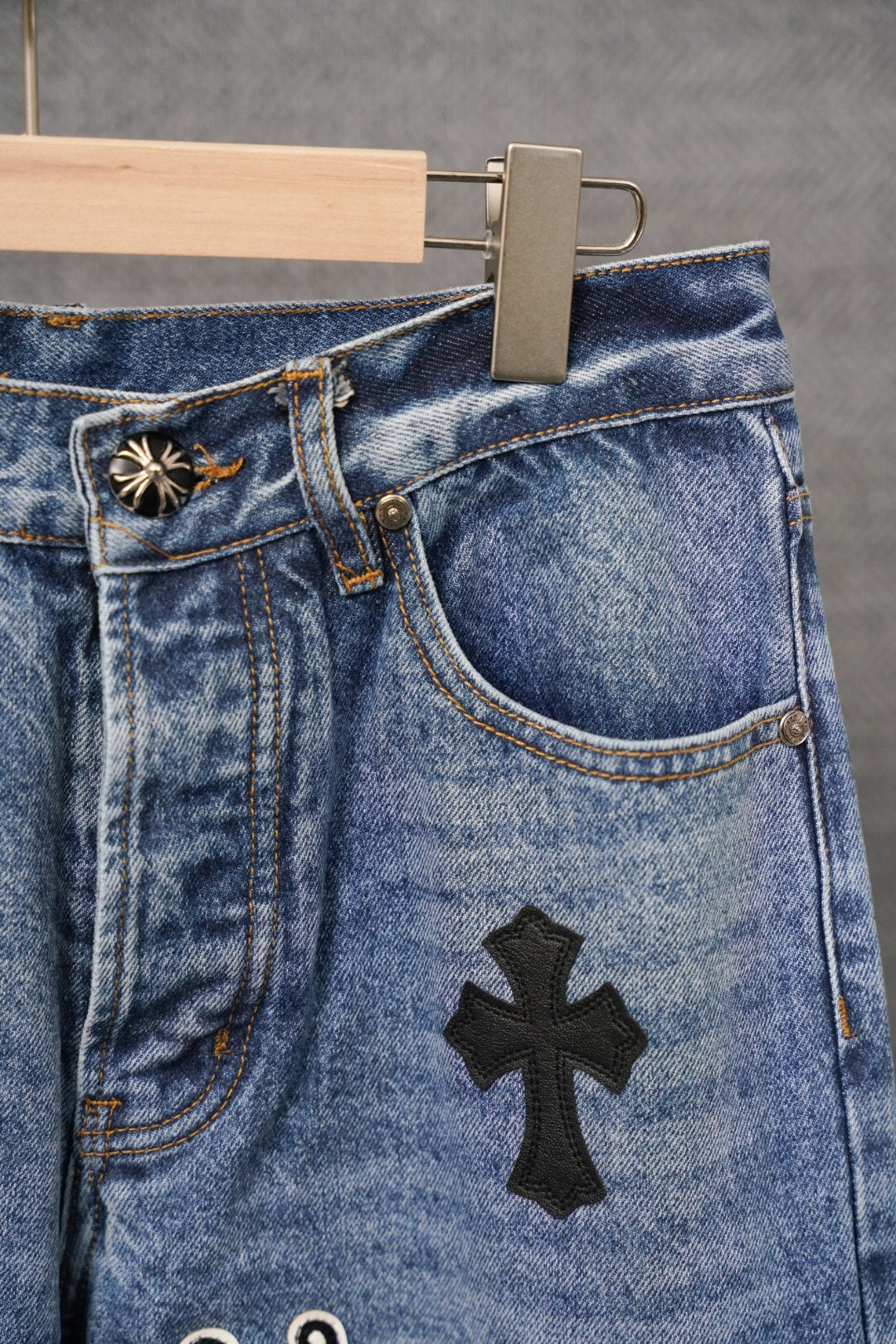 Light blue denim pants with curved pocket and black cross applique