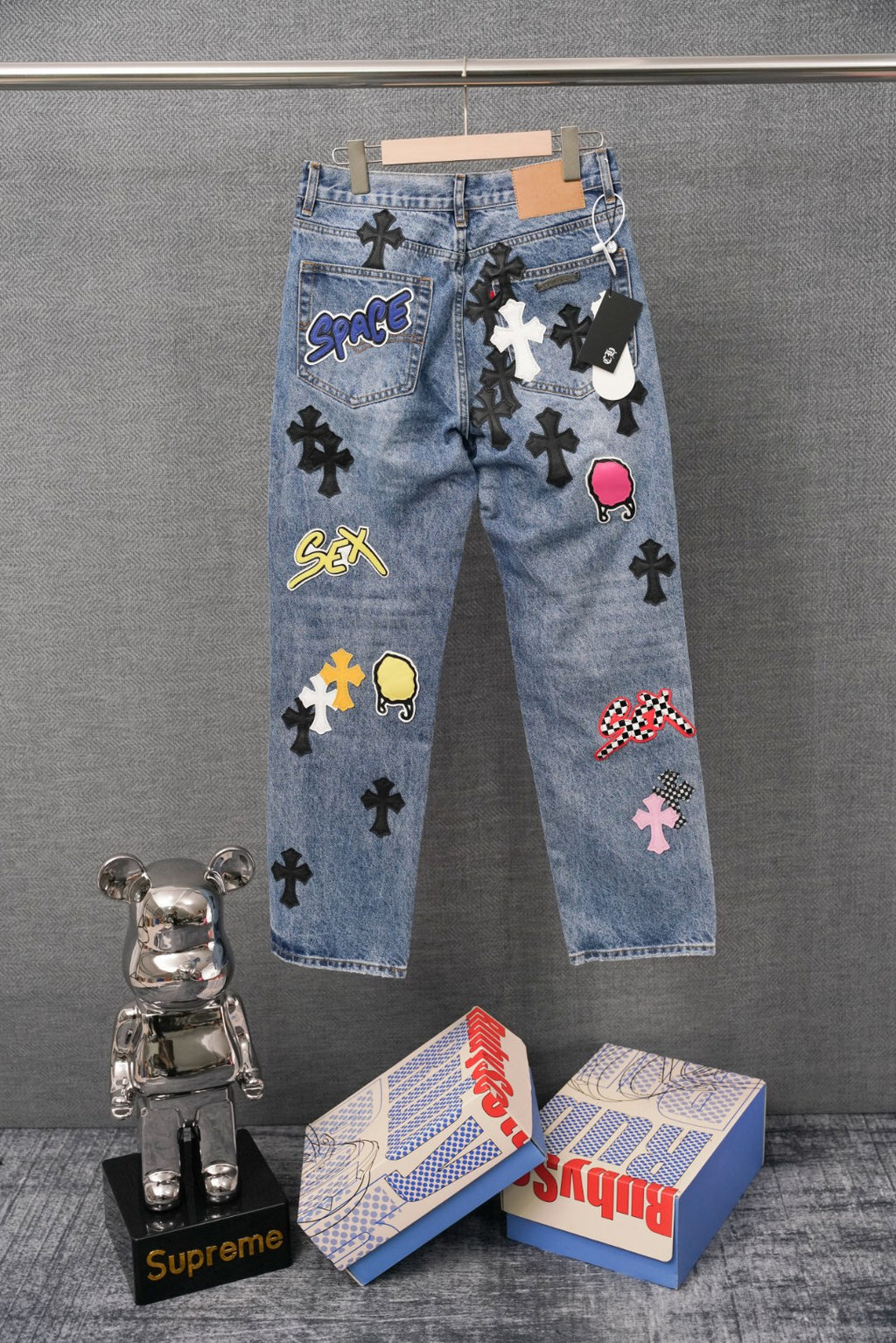Blue denim pants with colorful graphic patches and straight legs, side view.