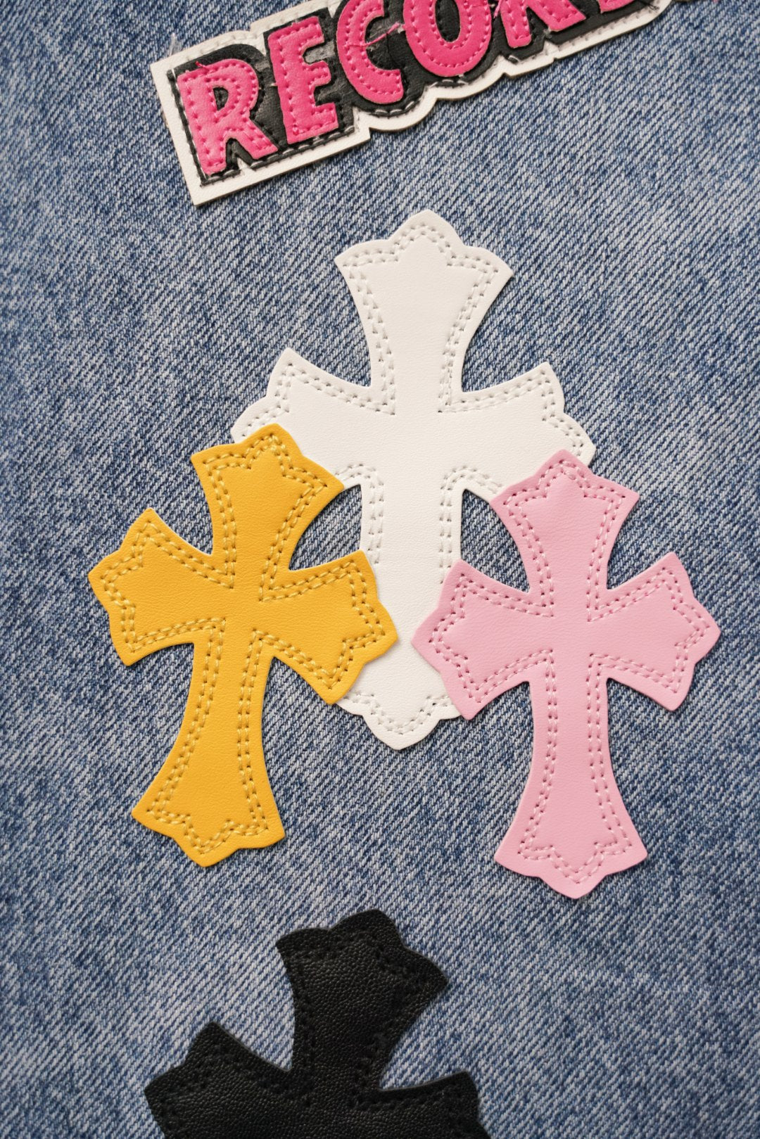 Light blue denim pants with RECORDS text and large cross patches in pink yellow