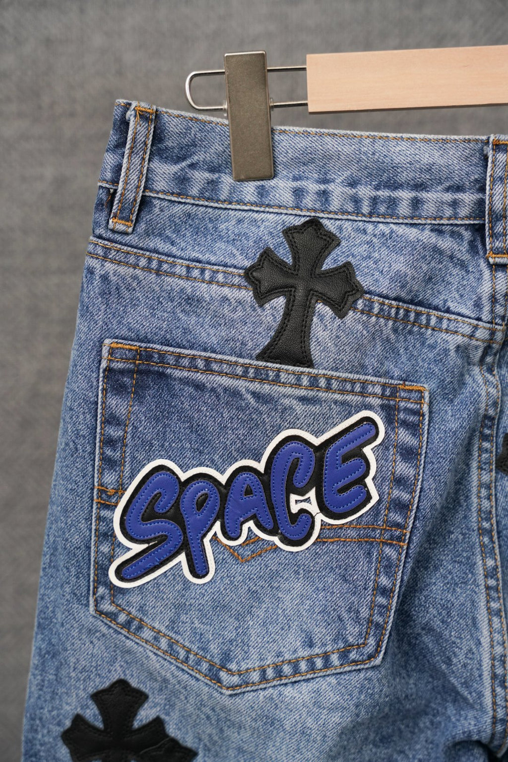 Blue denim pants with cross patches and a Space logo patch