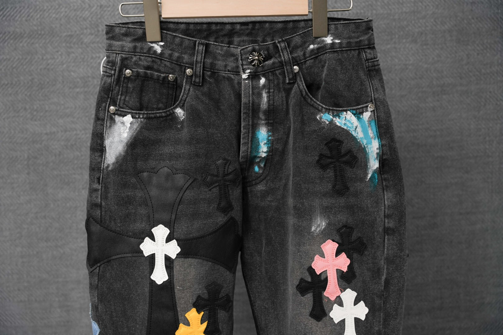 Black denim pants with front pocket cross patches and faded tie-dye panels