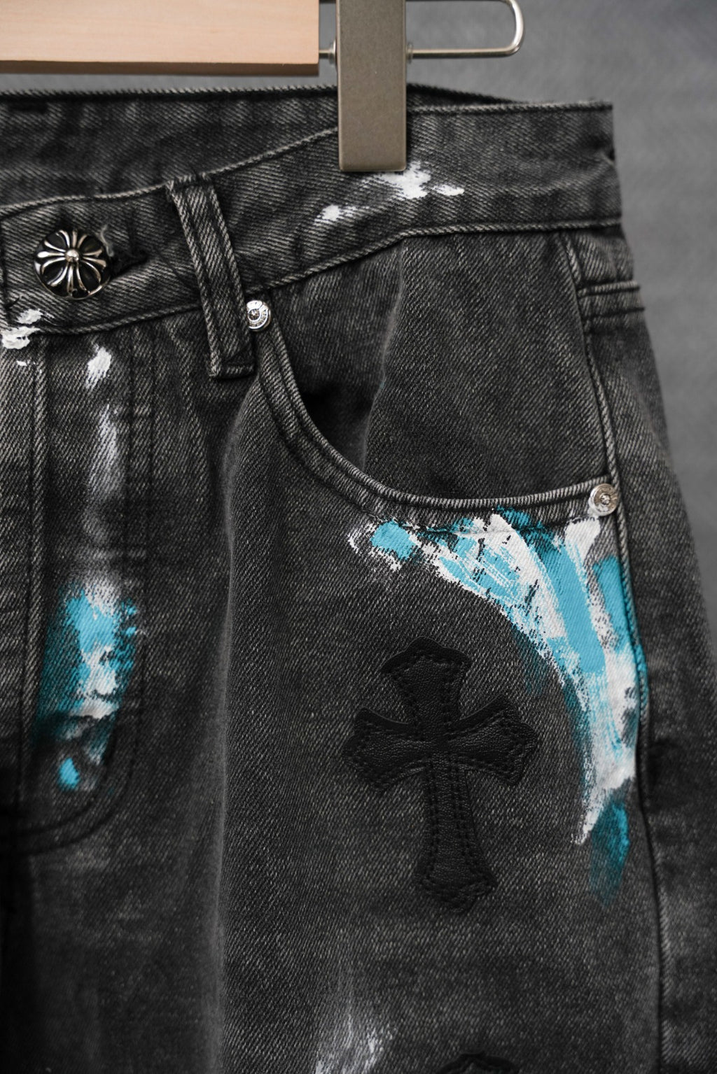 Black denim pants with coin pocket and blue cross patch print, distressed texture