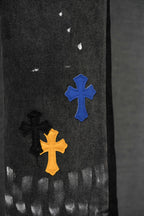 Dark denim pants with blue, orange, and black cross patches near the lower leg