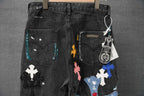 Black denim pants with colorful cross patches on front, belt loops and pockets