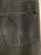 Front pocket close-up with metal button and visible stitching on dark gray denim