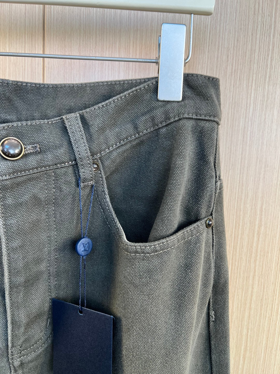 Waistband detail with belt loop, button closure, and front pocket with hanging tag