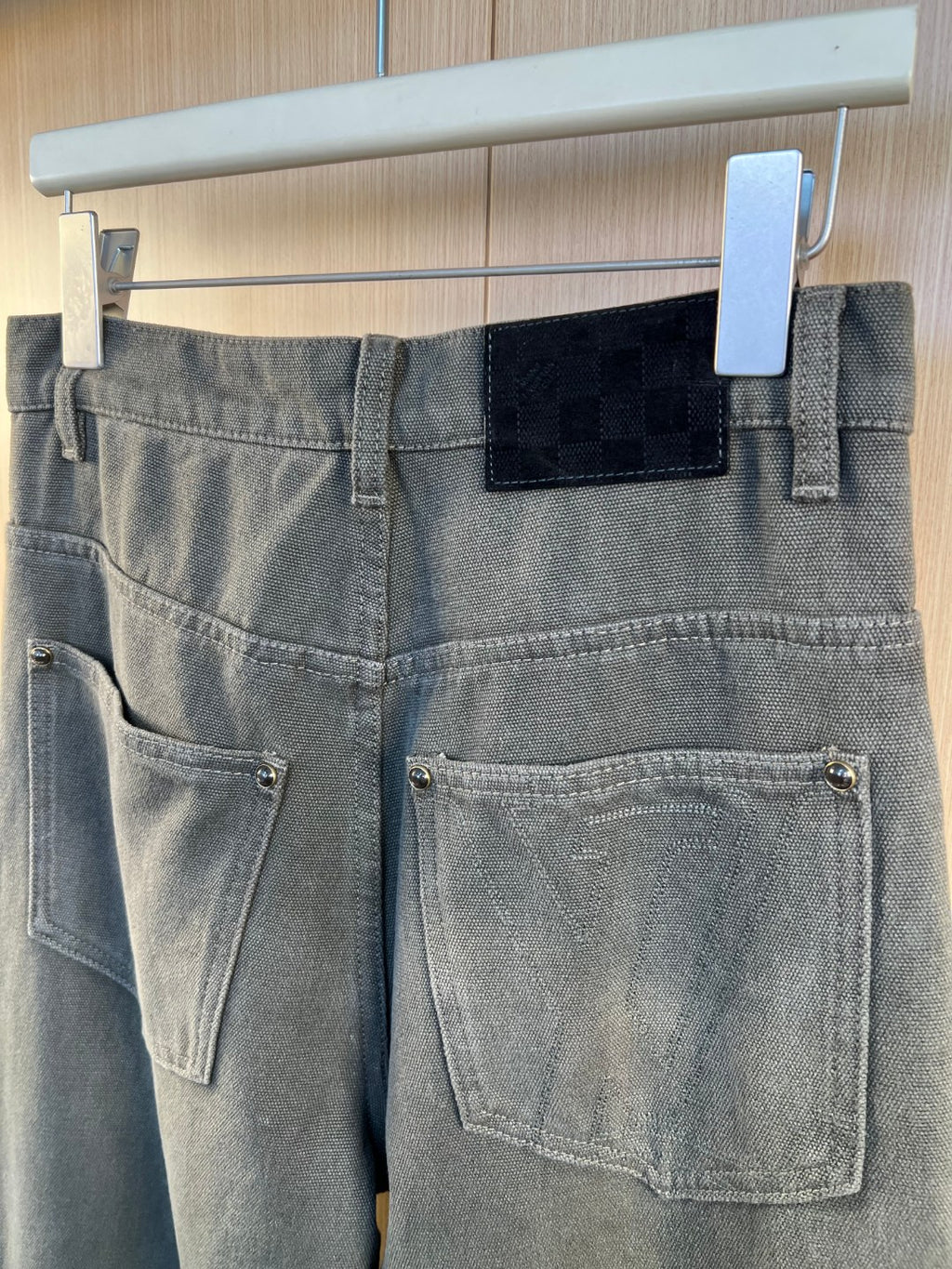 Waistband and front pockets with belt loops and rectangular patch on dark gray pants