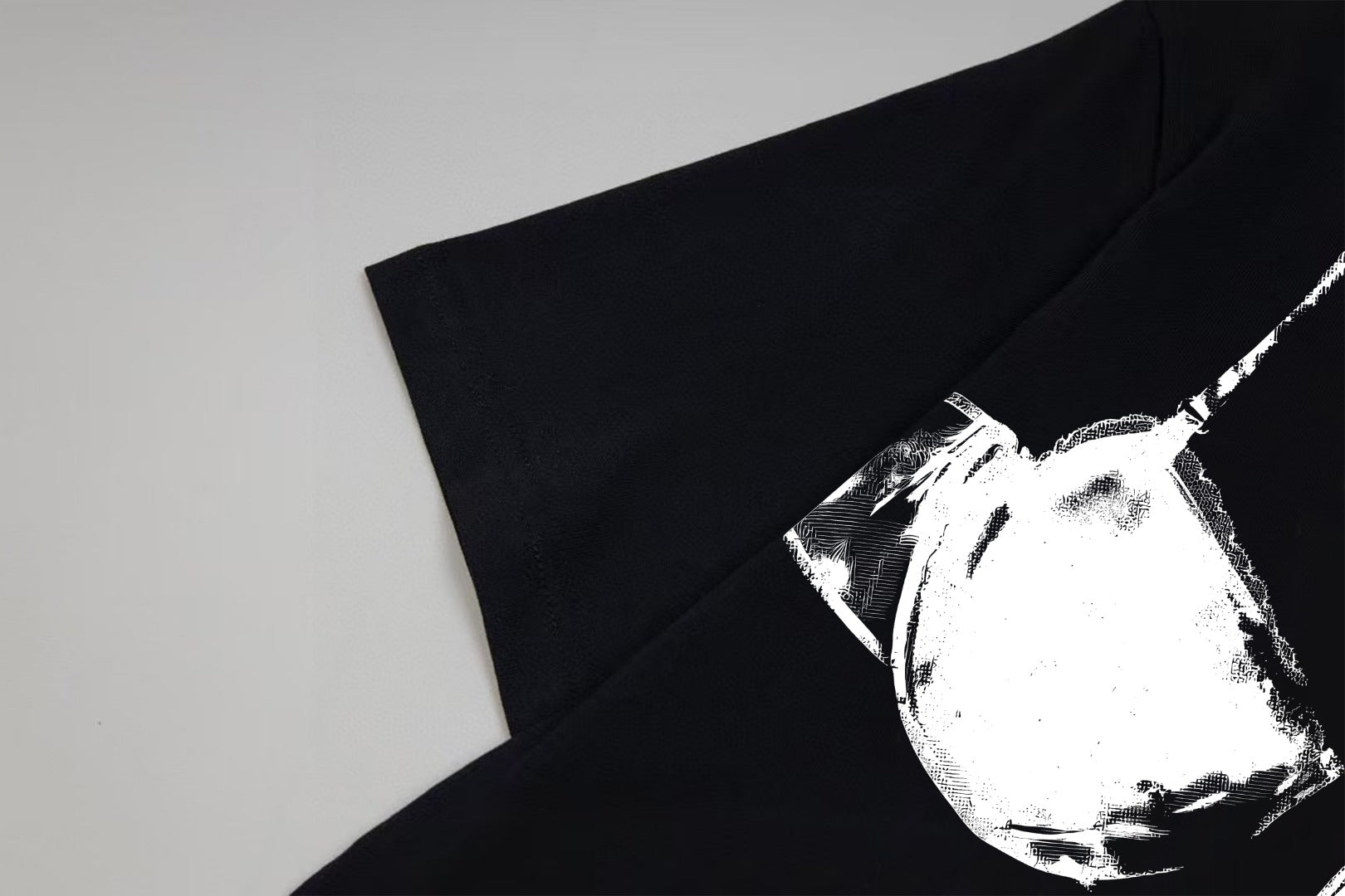 Black T-shirt sleeve and chest detail with white bust-print graphic