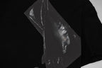 Close-up of silver-toned portrait graphic print on a black T-shirt