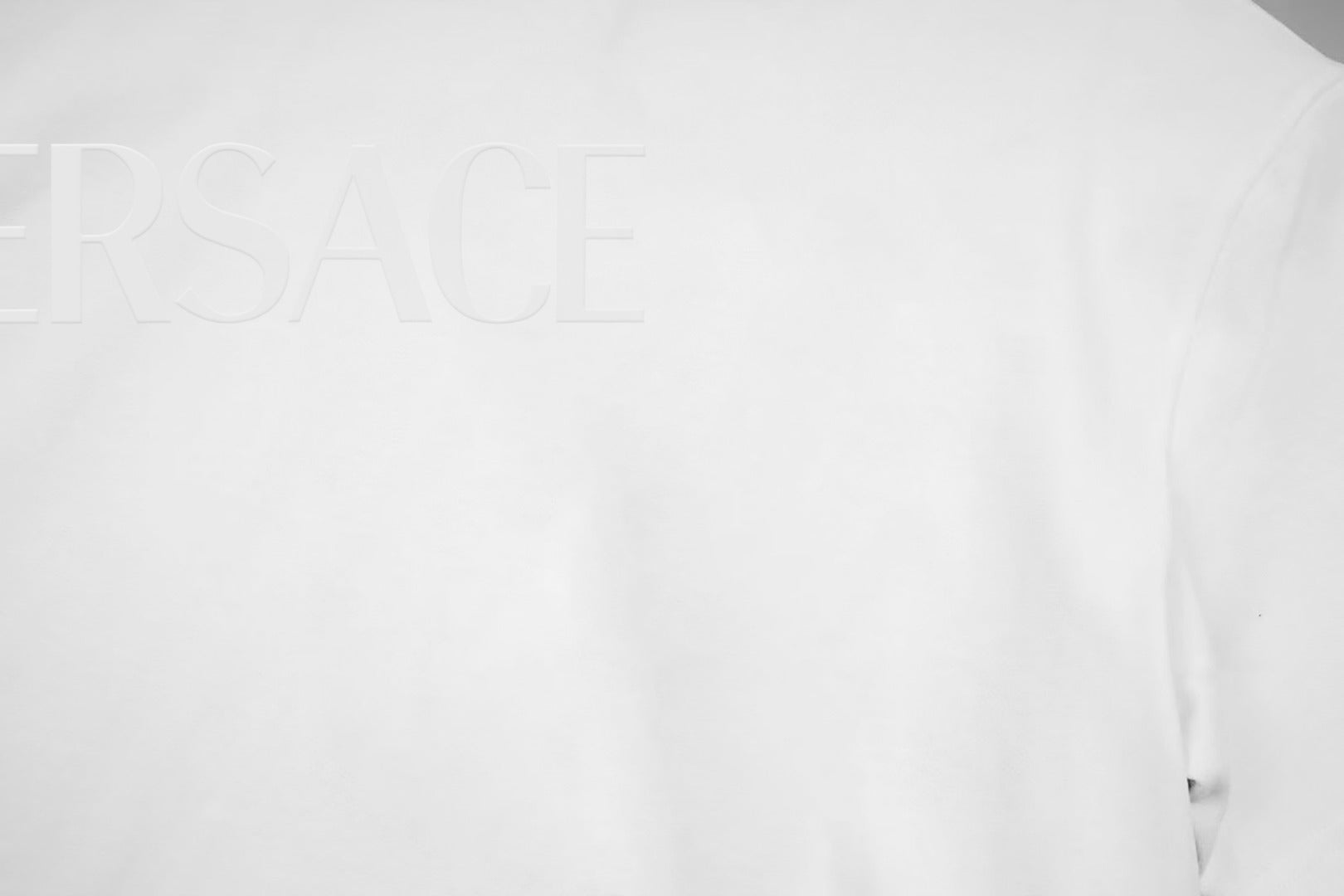 White T-shirt chest close-up with partial VERSACE text logo