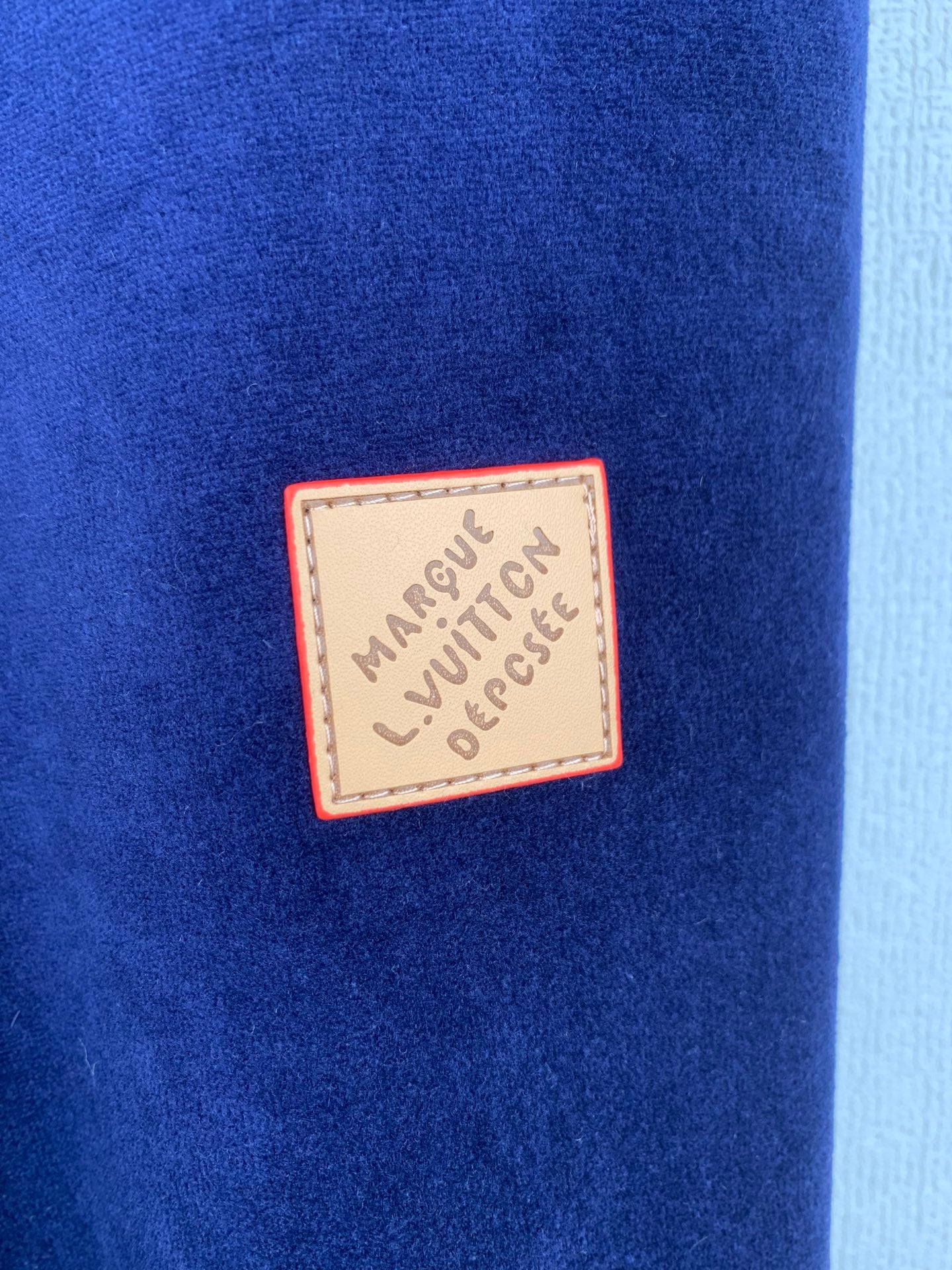 Close-up of dark blue fabric with a Louis Vuitton logo patch