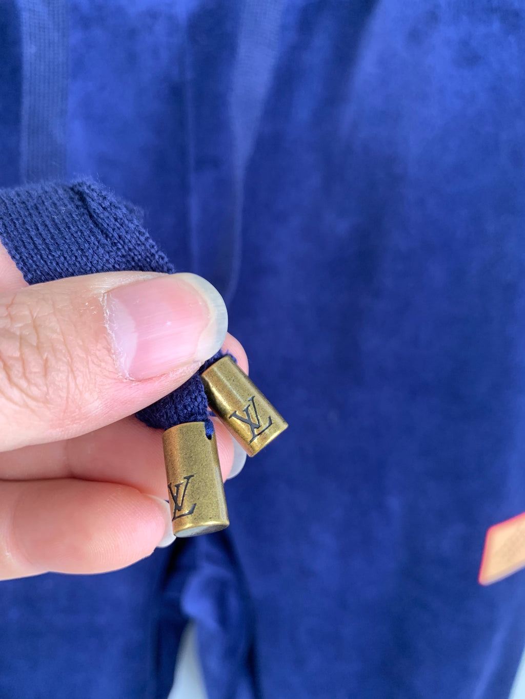 Drawstring cord with small gold clip on dark blue sweatpants