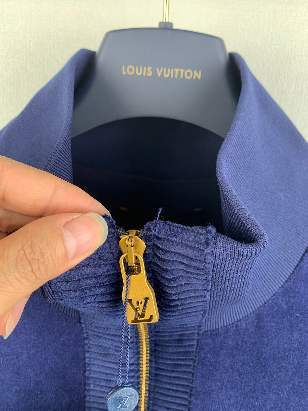 Blue Louis Vuitton jacket zipper pull detail with gold LV charm and ribbed collar