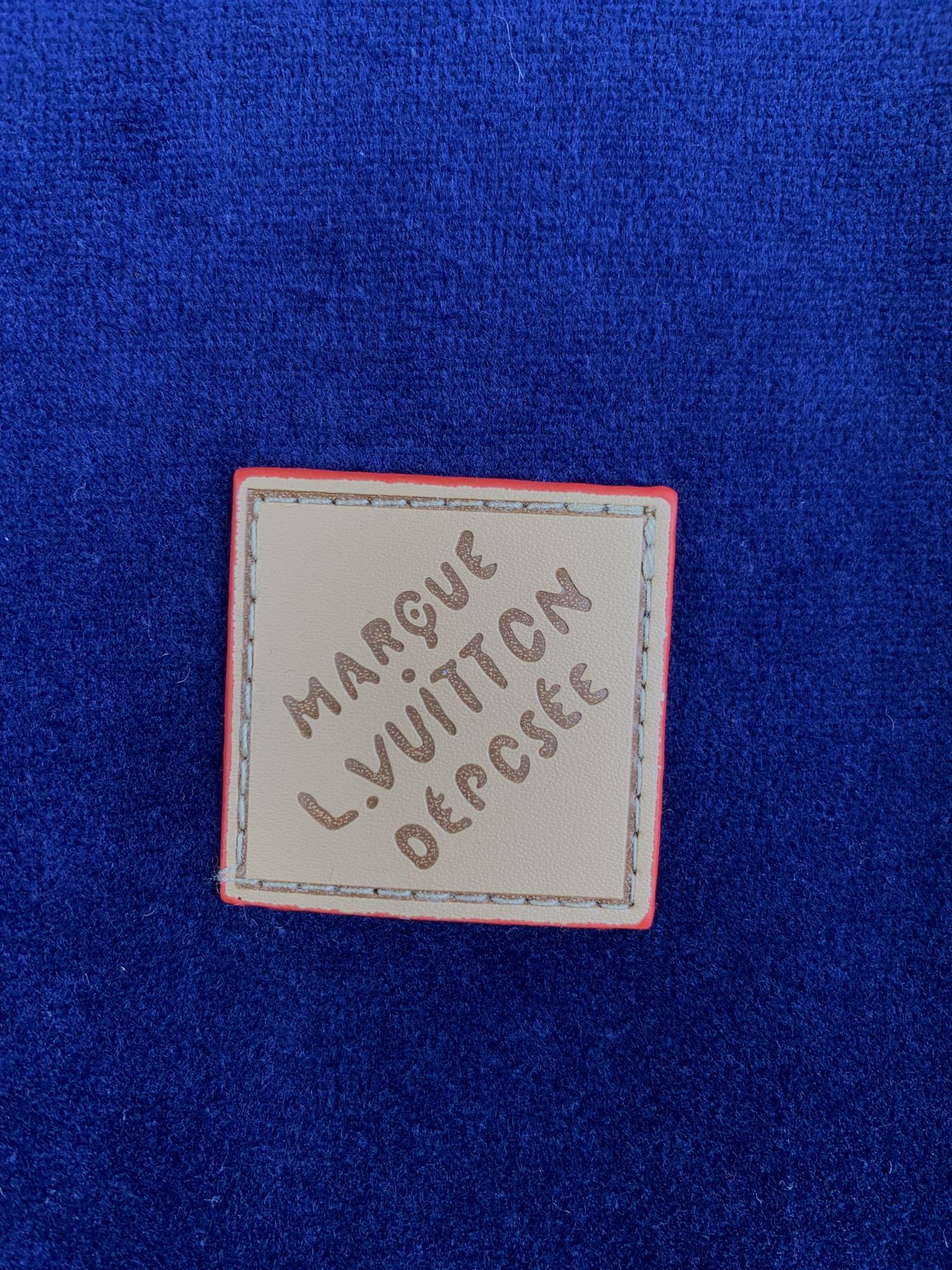 Louis Vuitton leather logo patch on blue jacket with handwritten-style text