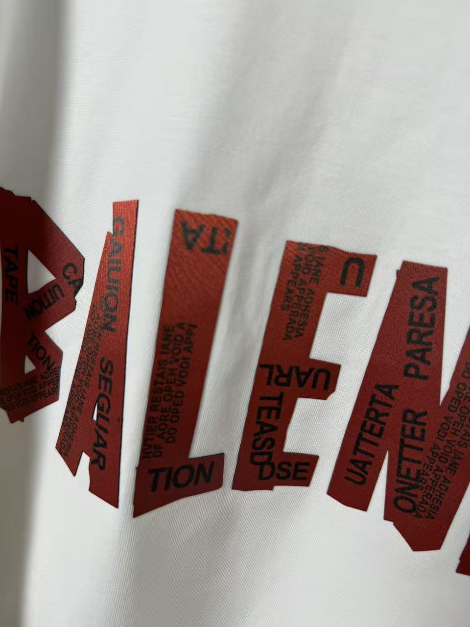 White T-shirt fabric close-up with red stacked logo text