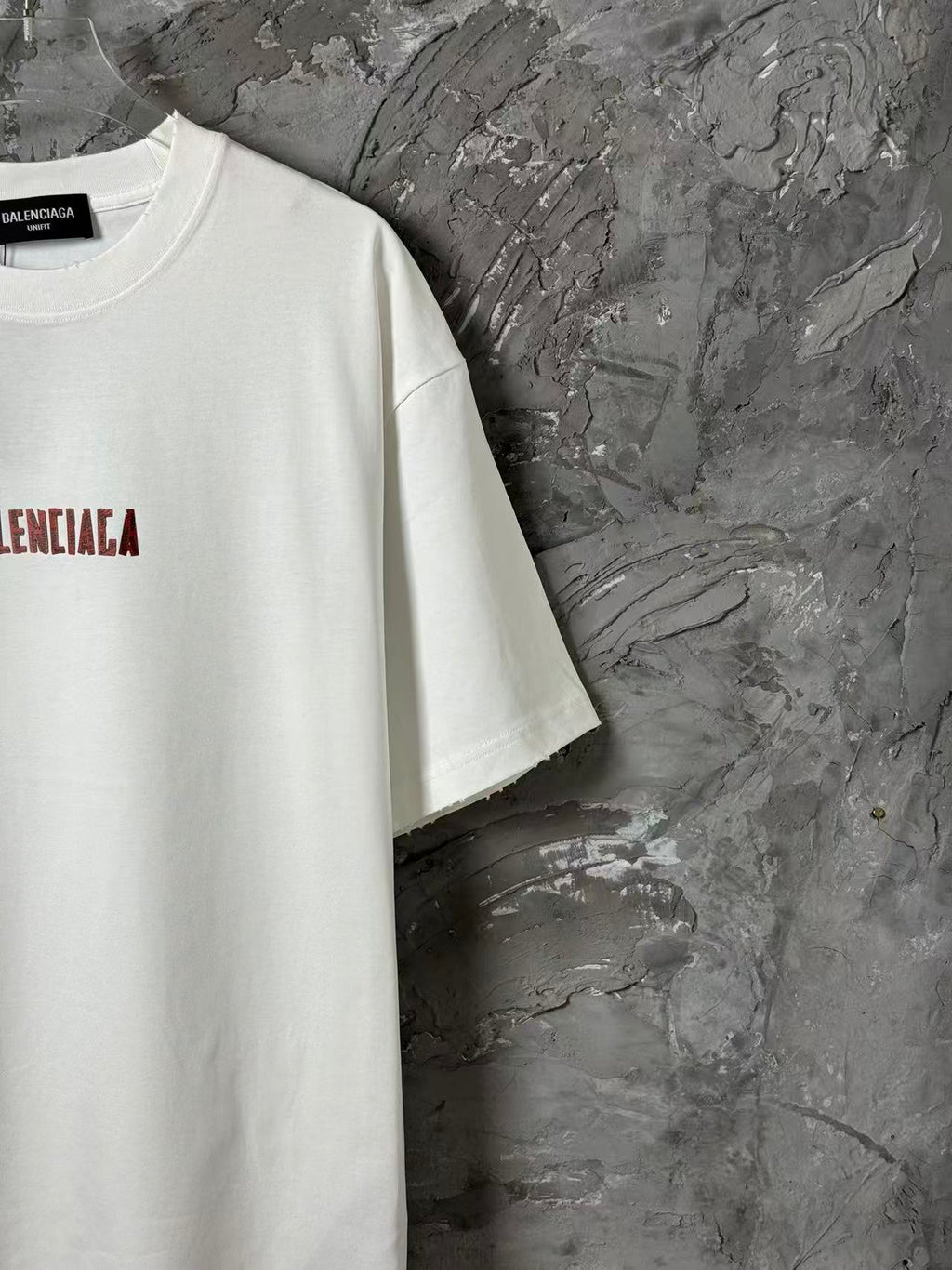 White short-sleeve T-shirt side view with red logo print near chest