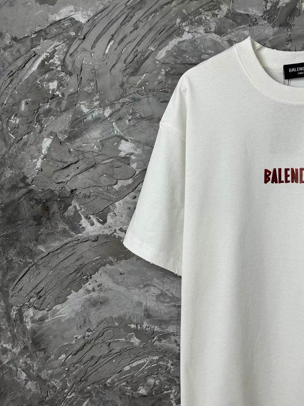 White short-sleeve T-shirt with partial red logo on right chest