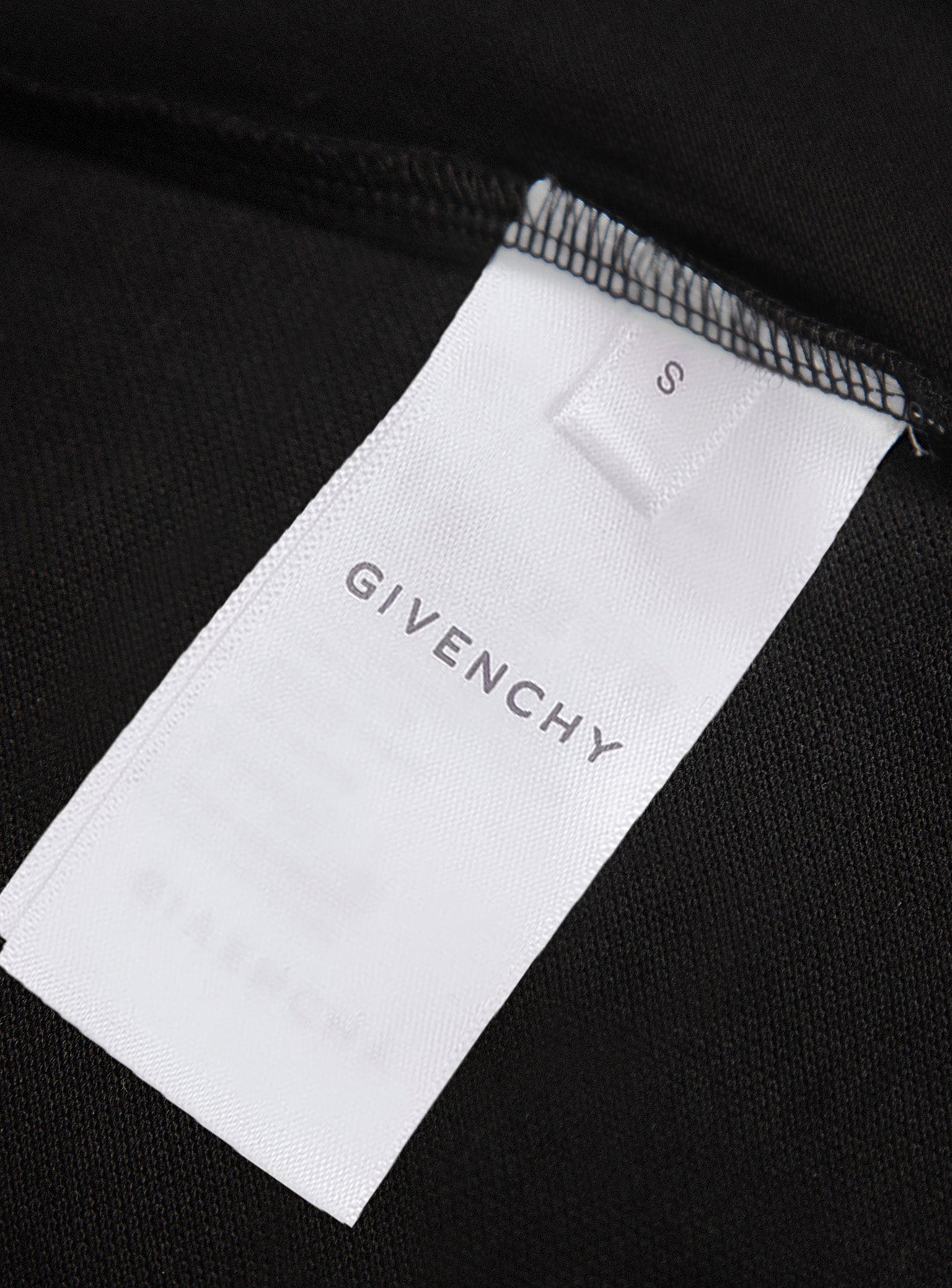 White size label marked S on black polo shirt