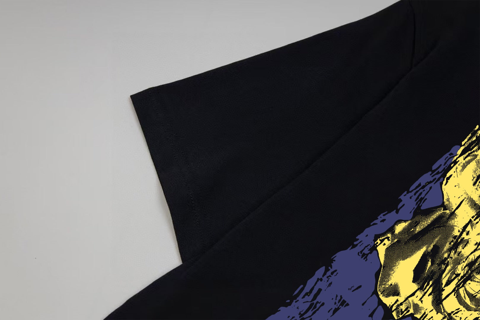 Black T-shirt sleeve and shoulder with yellow graphic detail