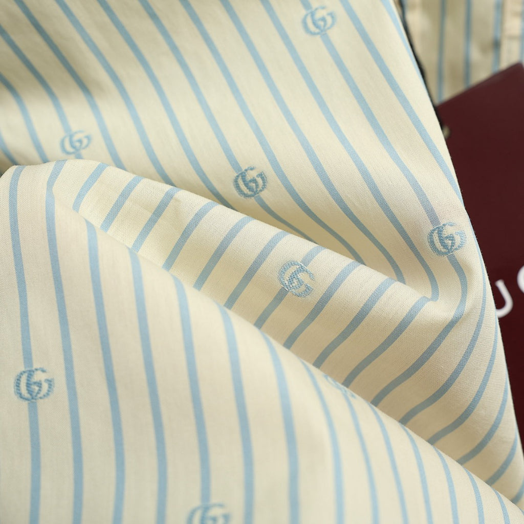 Light blue striped shirt fabric close-up with GG logo print