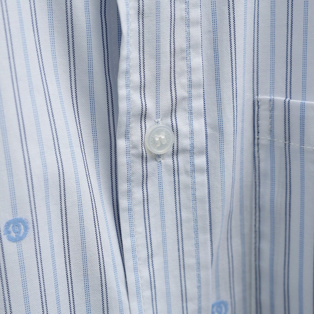 Short-sleeve button-up shirt button close-up on blue striped fabric