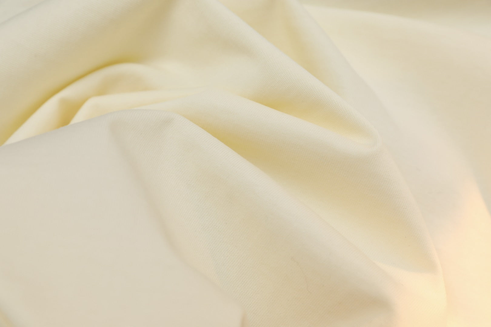 Cream Gucci T-shirt fabric close-up with soft drape texture.