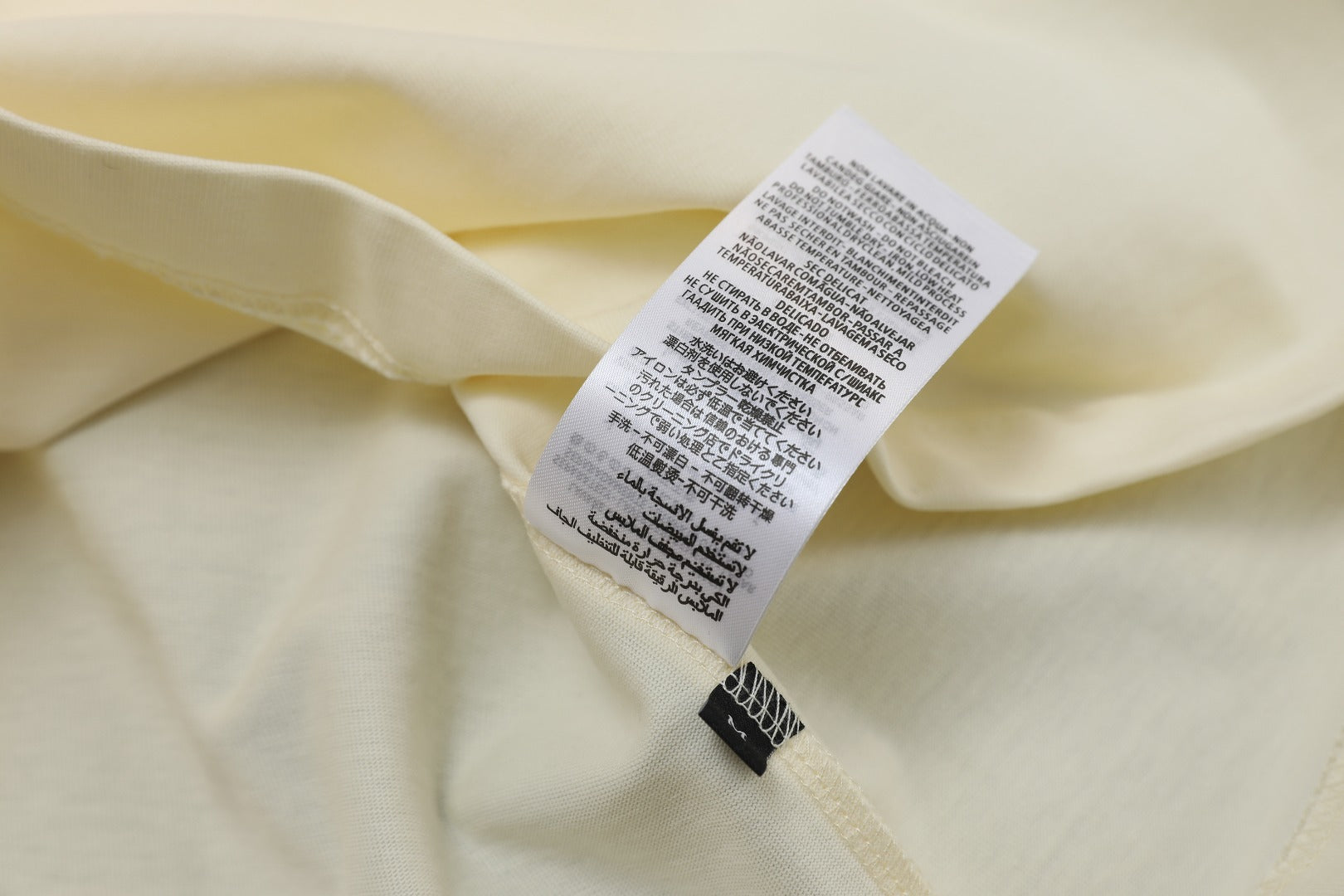 Cream T-shirt care label at inside neck opening
