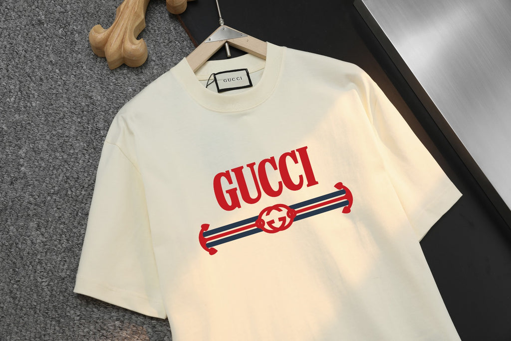 Cream Gucci T-shirt with red stripe logo graphic and GUCCI text, front close-up.