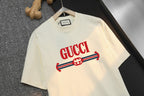 Cream Gucci T-shirt with red stripe logo graphic and GUCCI text, front close-up.