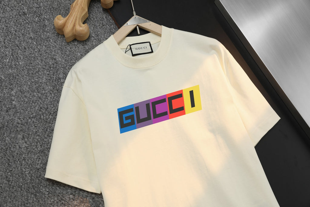Cream Gucci T-shirt close-up, bold multicolor logo across chest, crew neck.