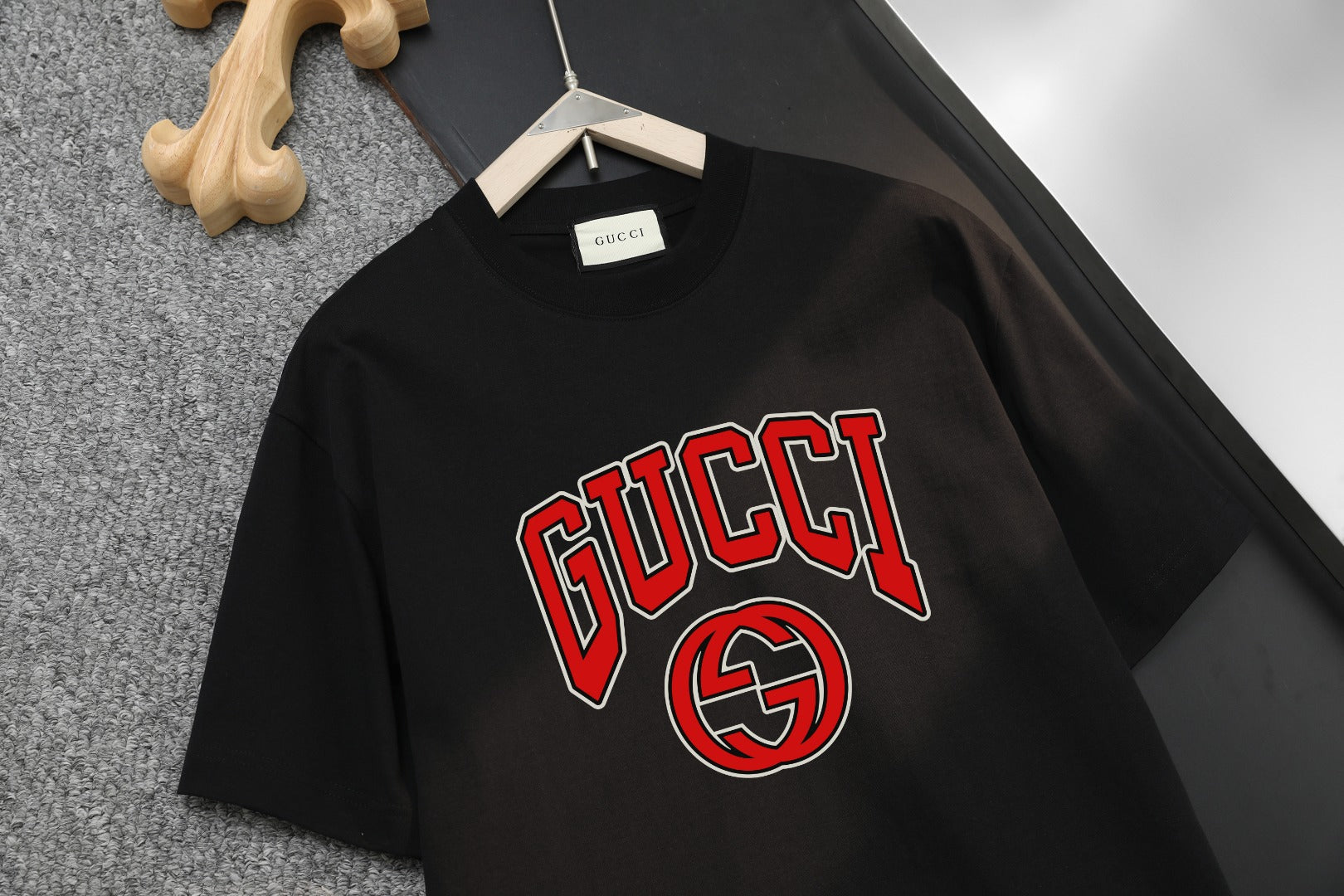 Black T-shirt with large GUCCI lettering and GG emblem graphic on the chest