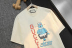 Light cream Gucci graphic T-shirt, centered cartoon and stacked GUCCI text
