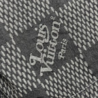 Louis Vuitton denim fabric detail with large white text on dark herringbone pattern