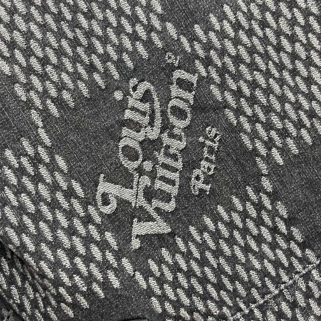Louis Vuitton denim fabric detail with large white text on dark herringbone pattern