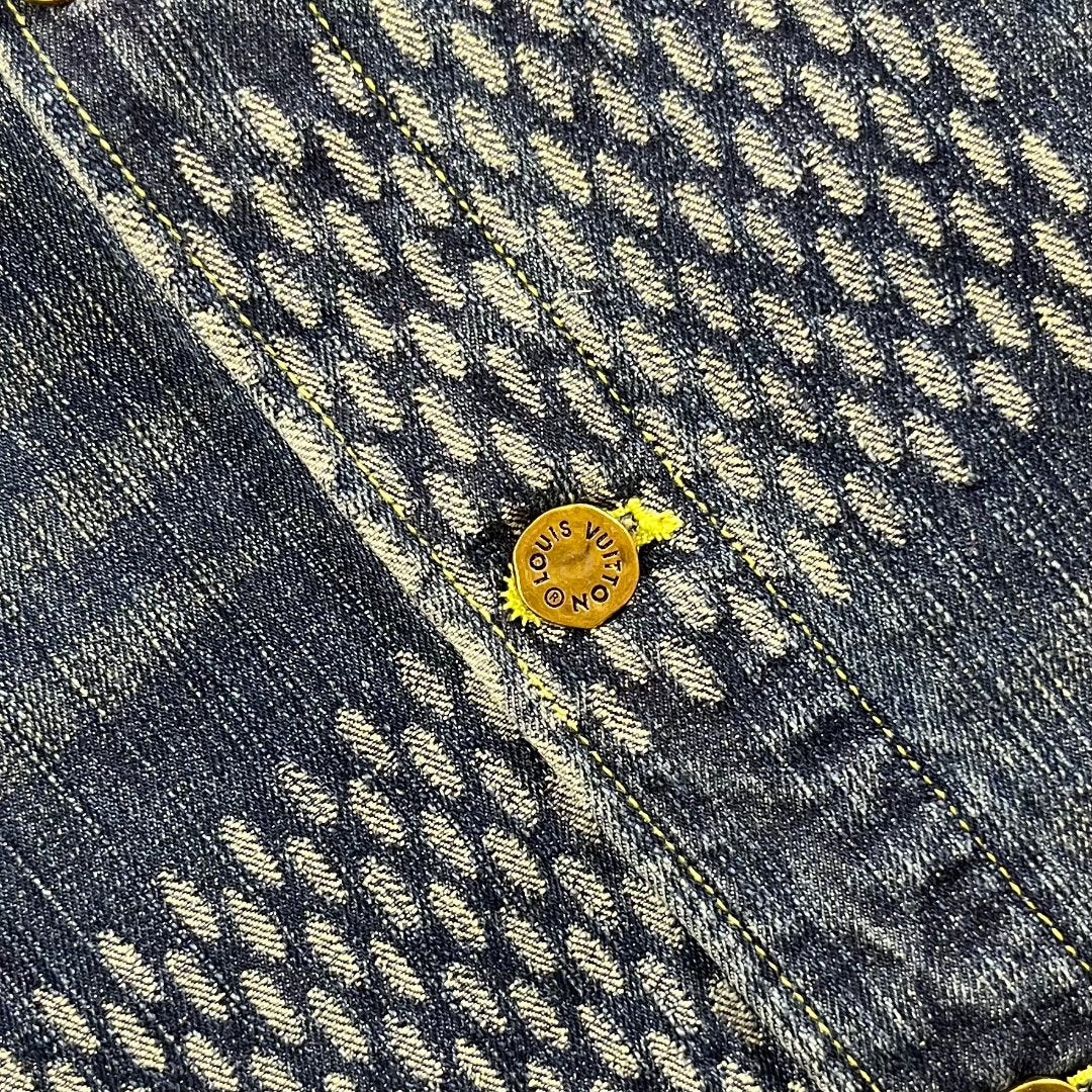 Denim fabric close-up with monogram pattern and small gold logo snap