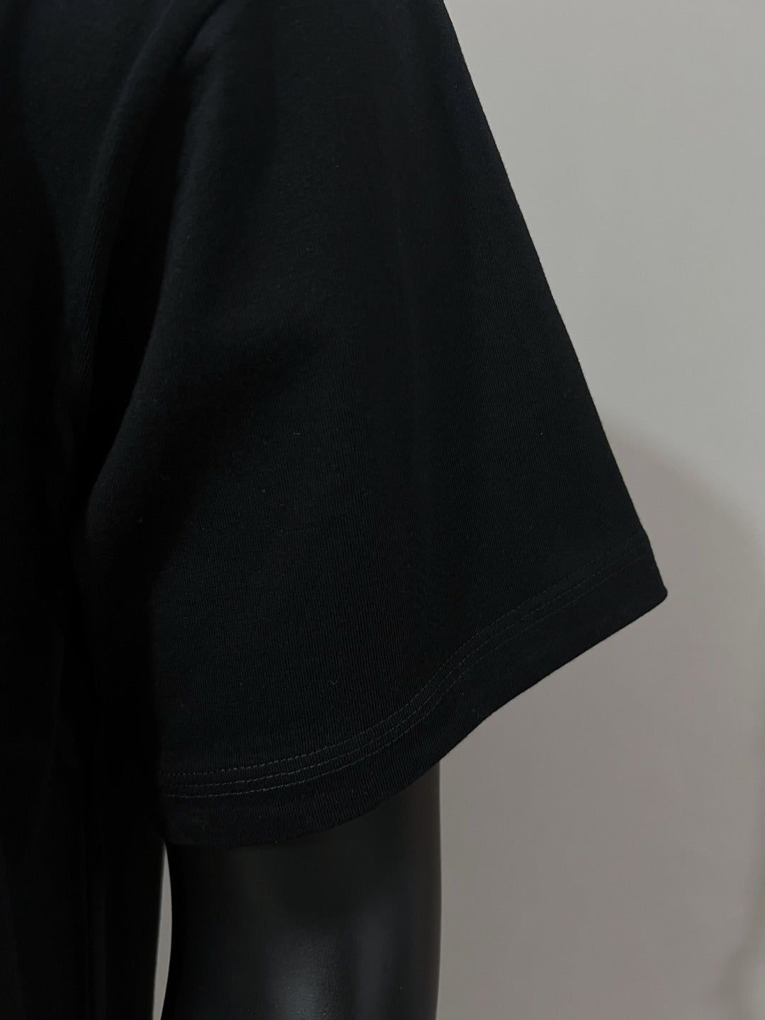 Black T-shirt short sleeve side view, hem stitching visible