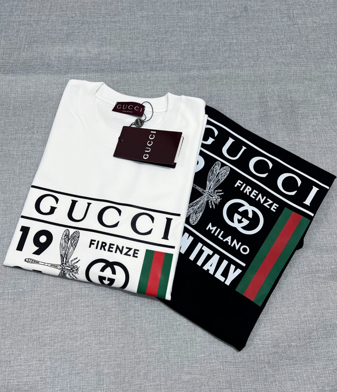 White and black Gucci graphic T-shirts with front prints on hangers