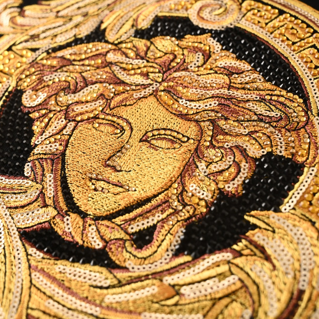 Gold Medusa crest sequin-style graphic detail on a black Versace T-shirt