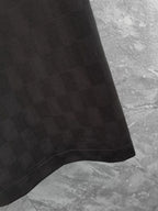 Louis Vuitton black polo shirt hem close-up, textured fabric and stitched edge