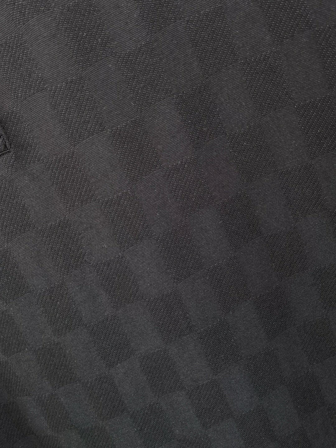 Louis Vuitton black polo shirt fabric close-up with subtle check pattern