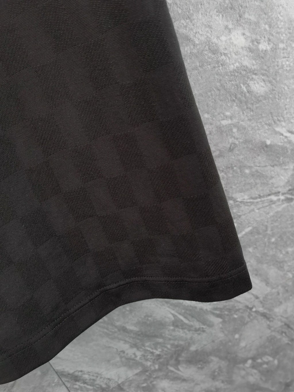 Black polo shirt hem detail with textured fabric