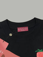 Black Gucci T-shirt collar with pink “GUCCI” label and strawberry chest graphic.